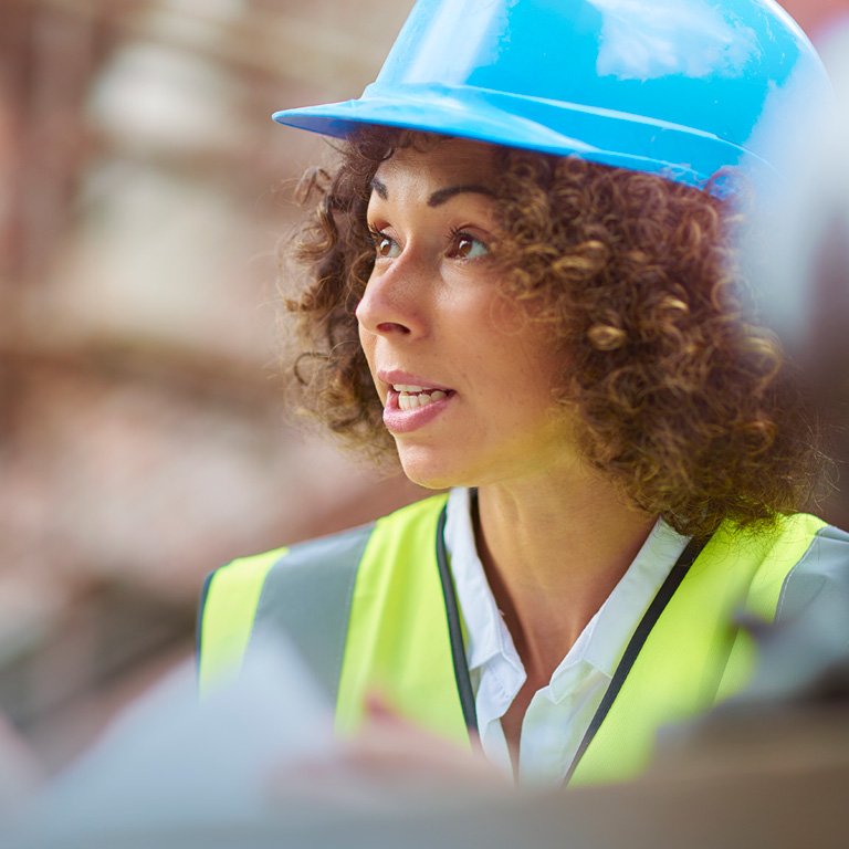 Construction worker on site in a blue hard hat looking up 