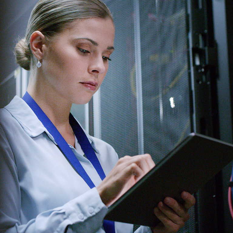Data centre worker reviewing tablet next to wires