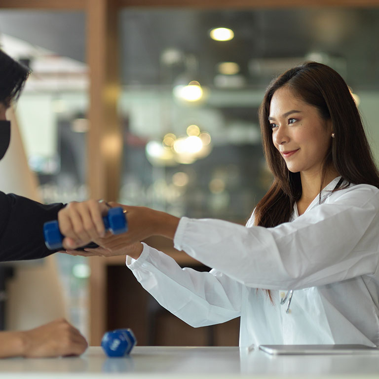 Attractive female therapist assisting male patient to do a physical therapy at health therapeutic centre