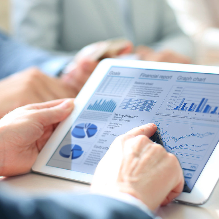 Business person analyzing financial statistics displayed on the tablet screen.