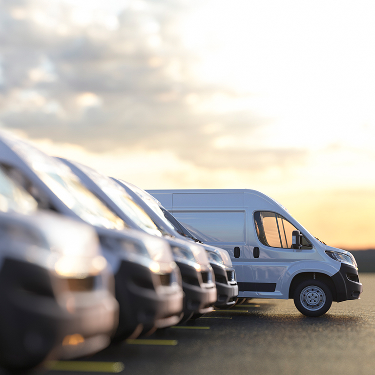 Fleet of delivery trucks, parked in a parking lot.
