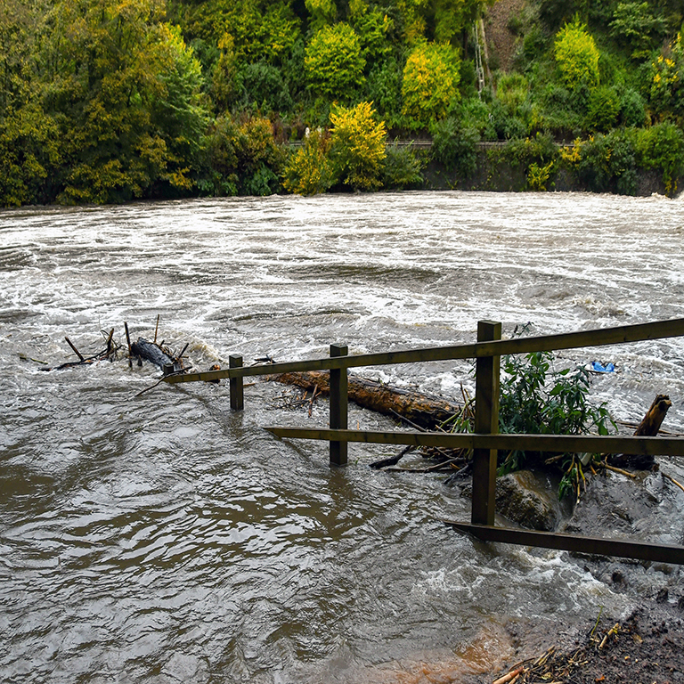 Submerged wooden fence on a river in heavy flood after a storm