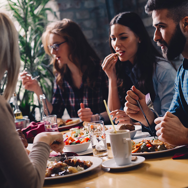 Group of happy diversed friends eating in restaurant