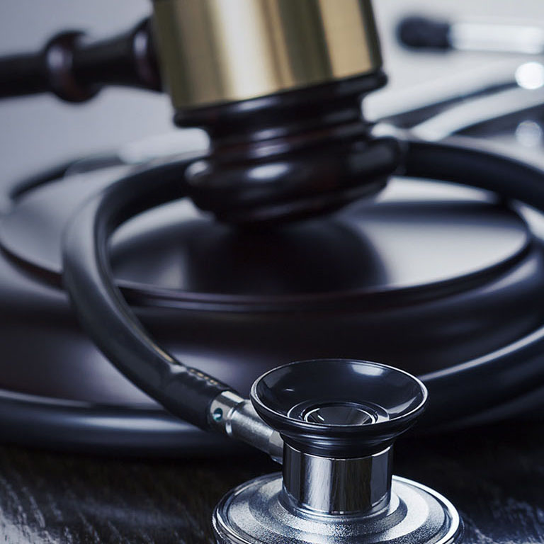 Gavel and Stethoscope on Reflective Wooden Table.