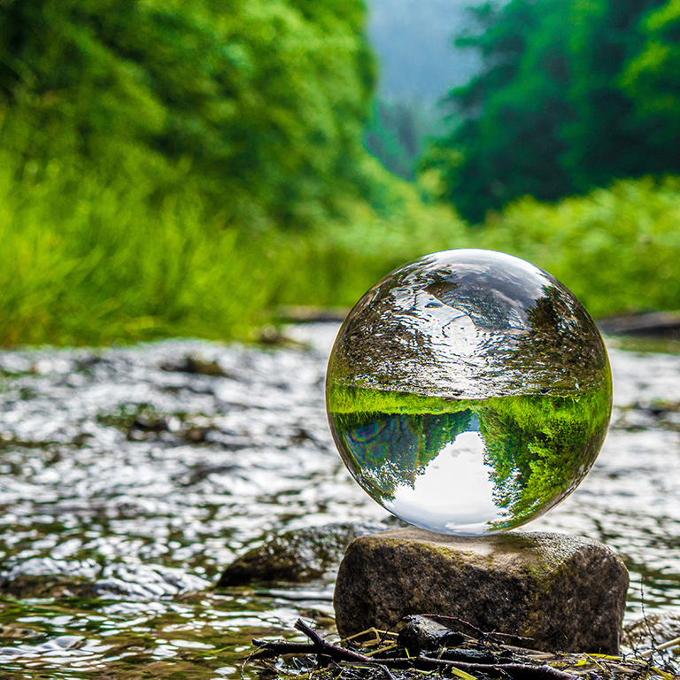 Glass sphere over a river with trees in nature — Climate neutral into the future concept - Net Zero 2050