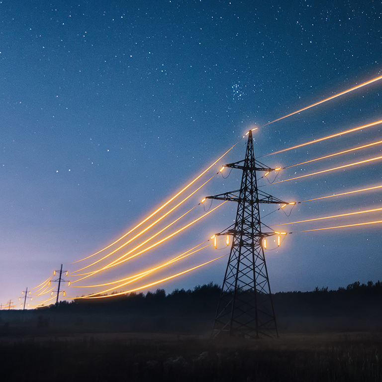 Electricity transmission towers with orange glowing wires the starry night sky. Energy infrastructure concept.