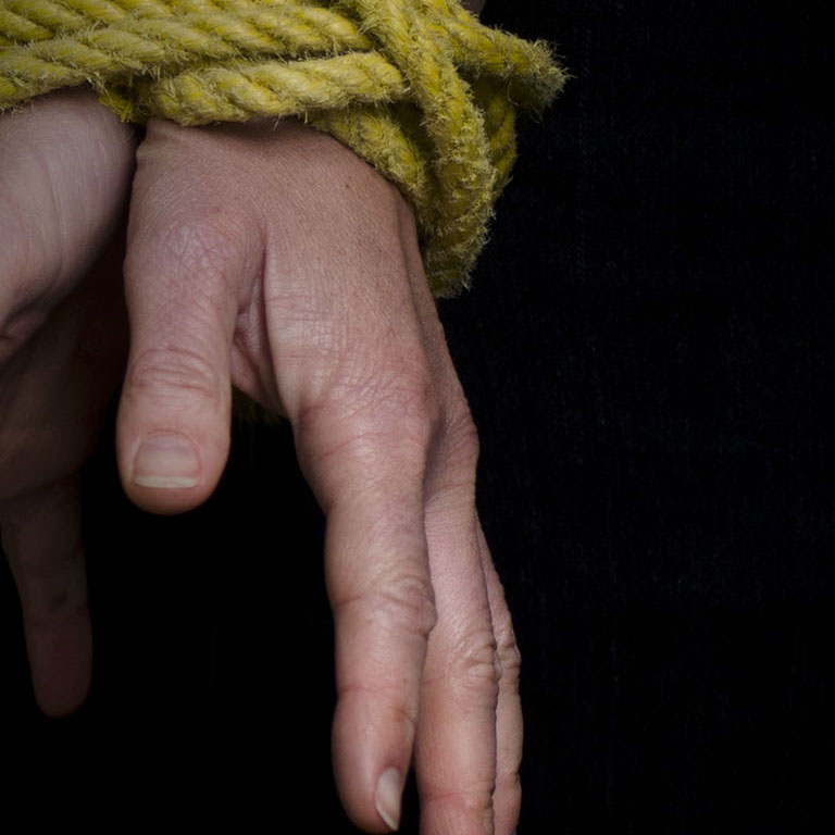 Hands of a missing kidnapped, abused, hostage, victim woman  tied up with rope in emotional stress and pain, afraid, restricted, trapped, call for help, struggle, terrified, locked in a cage cell.