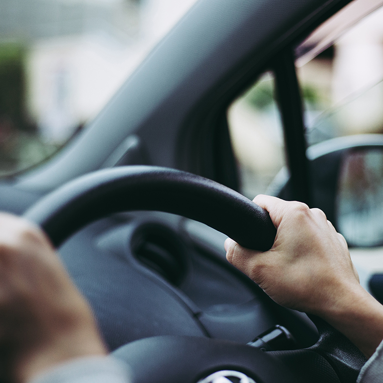 Close-up of hands on a steering wheel inside a car