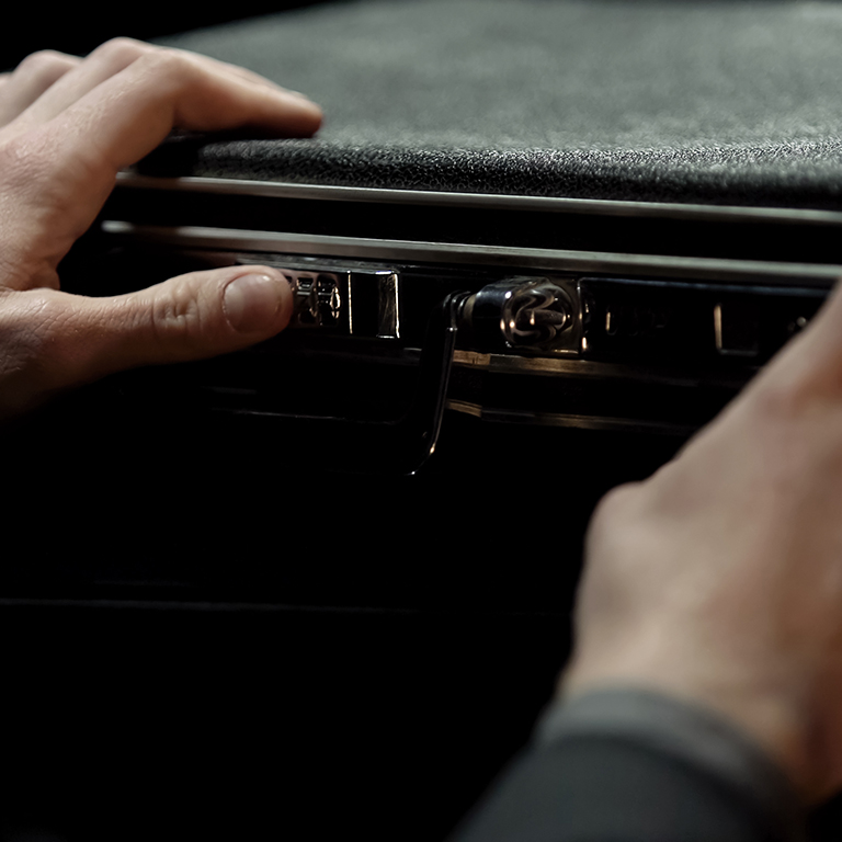 Close up of a pair of hands dailing code on a briefcase in the dark. Ransom concept.