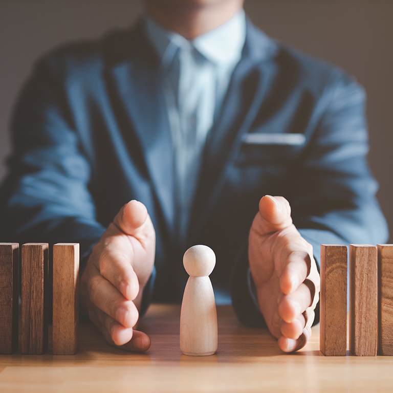 Risk management and assessment concept. Businessman prevent or protect his business and employee from high risk. Wood block represent of risk attack to business, two hands block and protect the domino