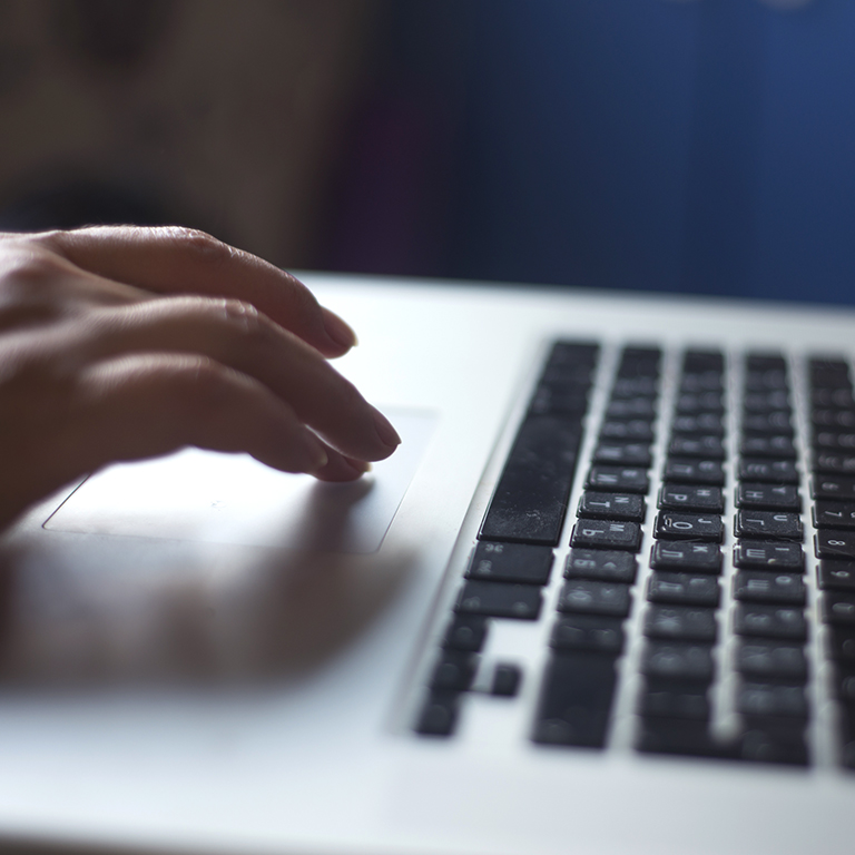 Hands typing on keyboard of a laptop in a dark room close up selective focus photo