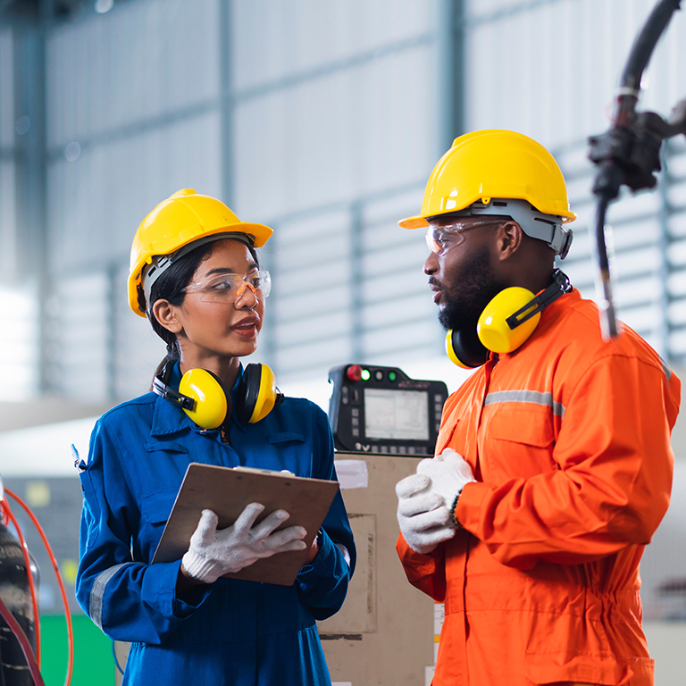 Diverse industrial workers in full safety gear talking.