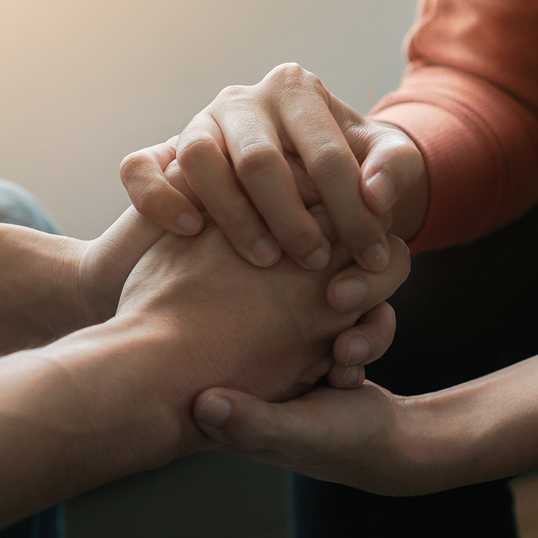 PTSD Mental health concept, Psychologist sitting and touch hand young depressed asian man for encouragement near window with low light environment.Selective focus.