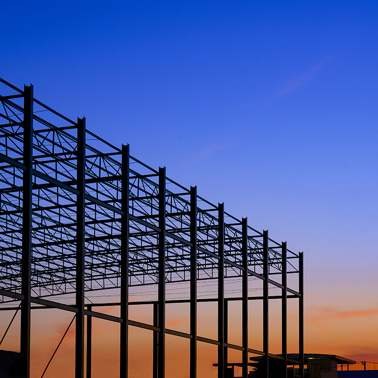 Silhouette low angle view of large industrial building structure in construction area against colorful twilight sky background