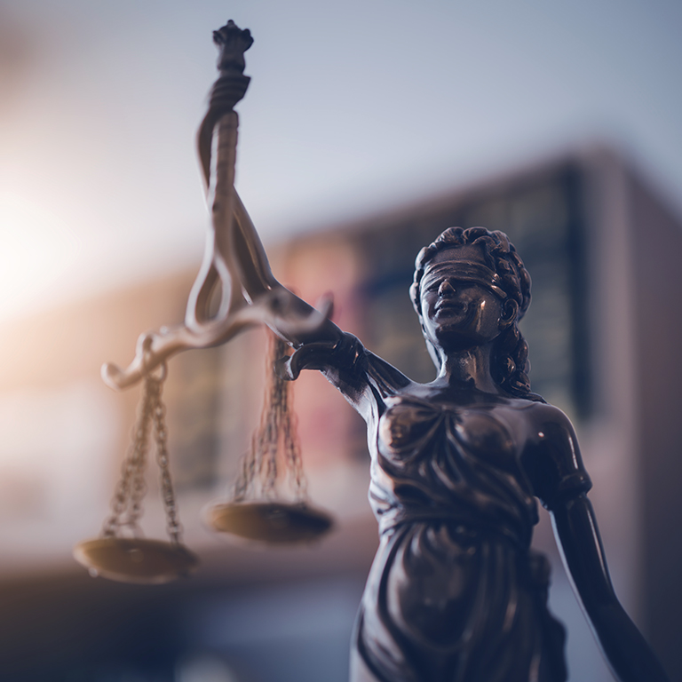 Closeup of Lady of Justice statue in front a bookcase in an office.	