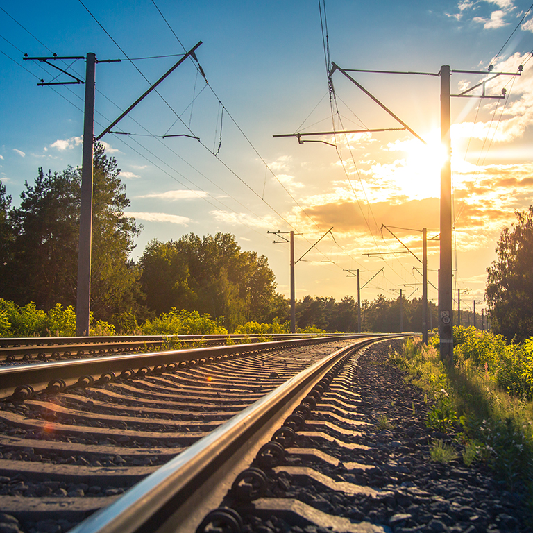 Industrial landscape with rails and railway. Railroad leaving into the distance against the sunset