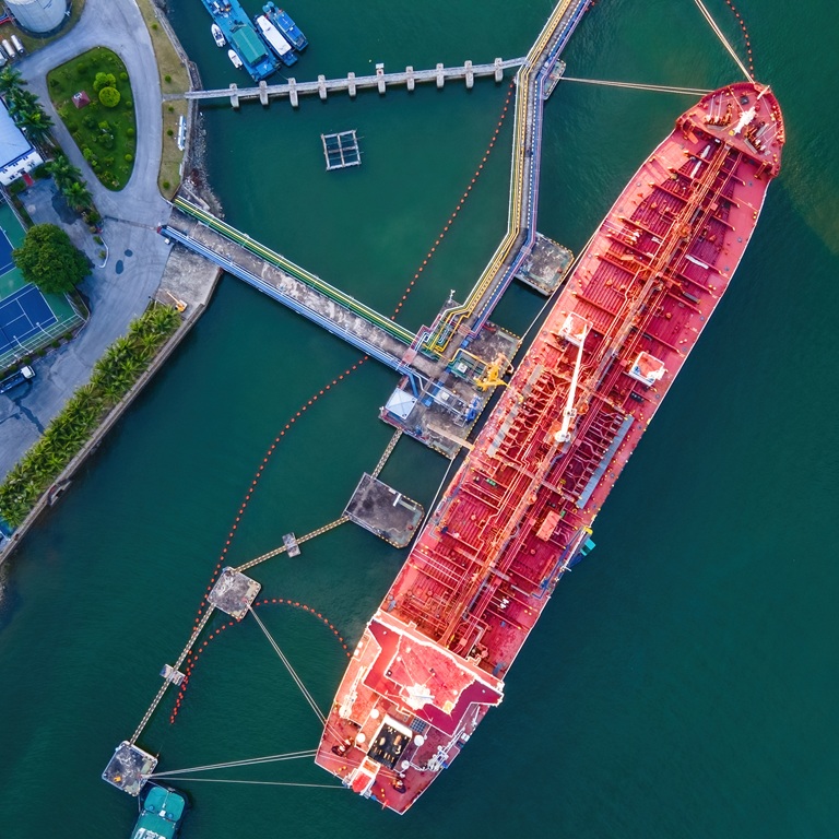 Large ship docked at port with smaller boat nearby