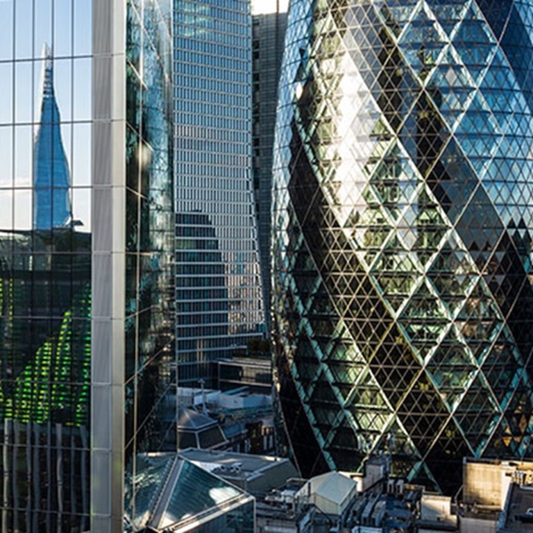 Contemporary skyscrapers in London, showcasing glass facades and reflections. The iconic Shard towers above its surroundings, creating a striking urban landscape.