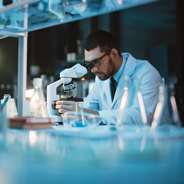 Medical development laboratory: scientist looking under microscope, analyzes petri dish sample. specialists working on medicine, biotechnology research in advanced pharma lab.