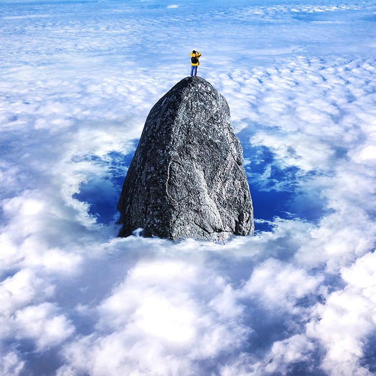 Man looking out on mountain peak through clouds