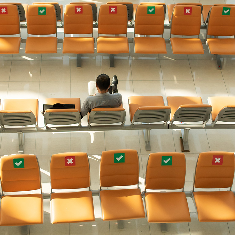 man on each chair twith social distancing sign on it