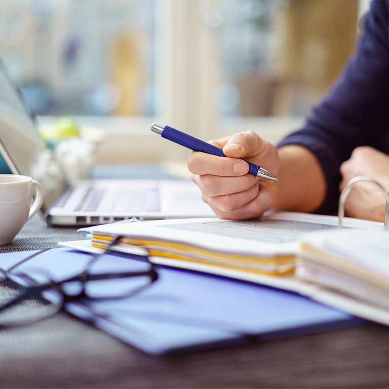 Businessman working on document with computer and pen