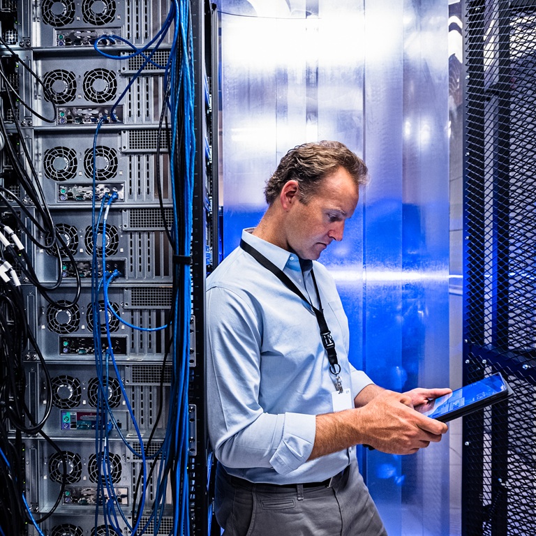 Man works with tablet inside data center