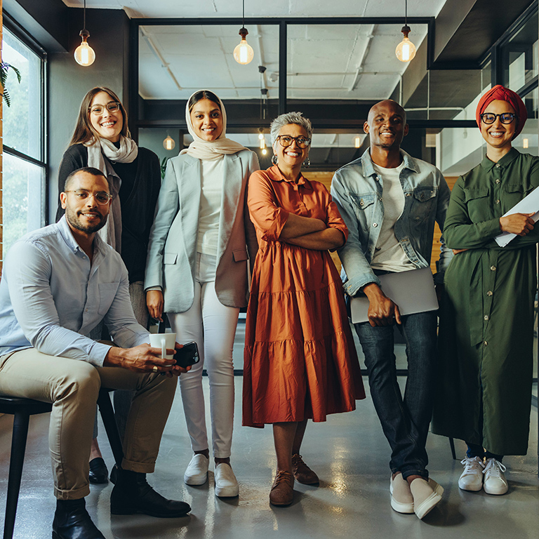 Team of diverse businesspeople smiling at the camera in a modern office. Group of multicultural entrepreneurs running a successful startup in an inclusive workplace.