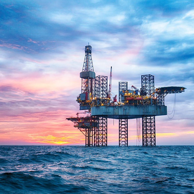 Offshore jack-up rig in the midle of the ocean at sunset