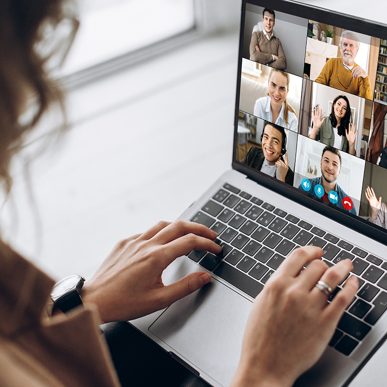 Back view of female employee communicate on video call with diversed colleagues, woman worker conducts webcam group conference with business partners uses laptop and app