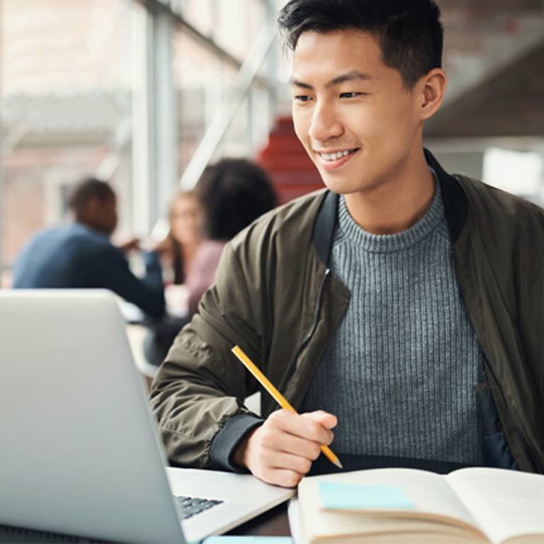 Student studying online and preparing for exams with digital devices and books