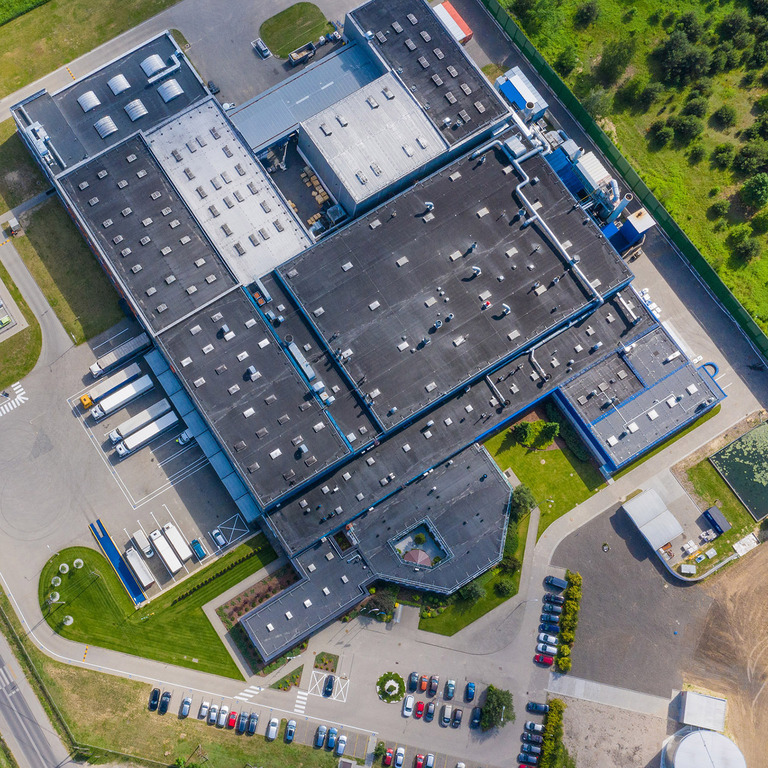 Aerial view of goods warehouse. Logistics center in industrial city zone from above. Aerial view of trucks loading at logistic center