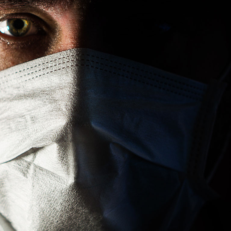 portrait of a man in a medical mask in a low key. a worldwide tragedy. COVID-19 virus pandemic warning.