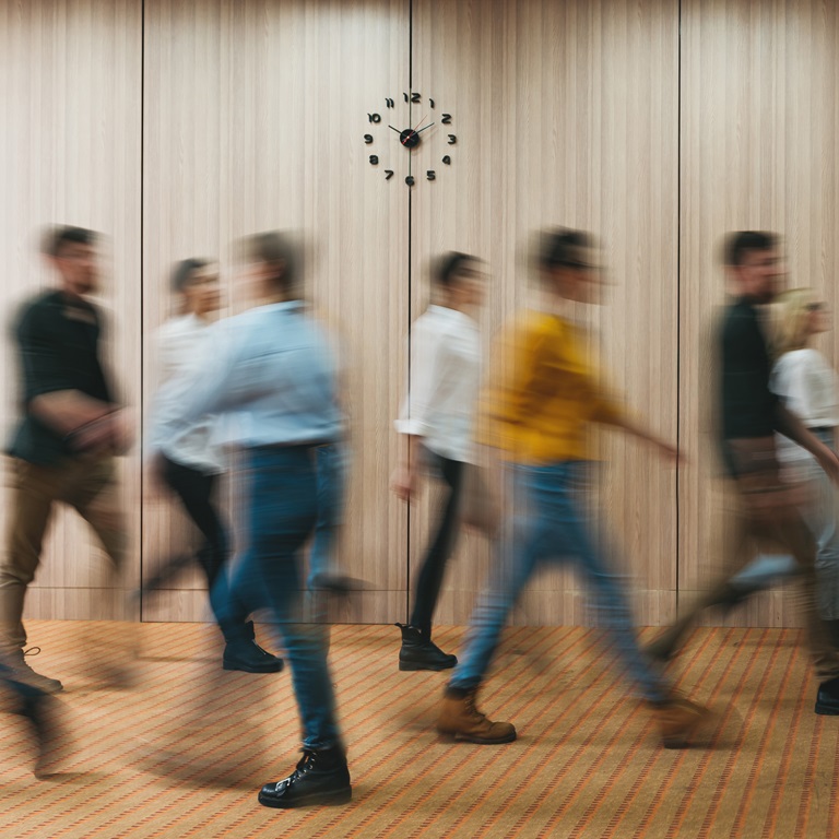 People walking in a hallway with a clock on the wall