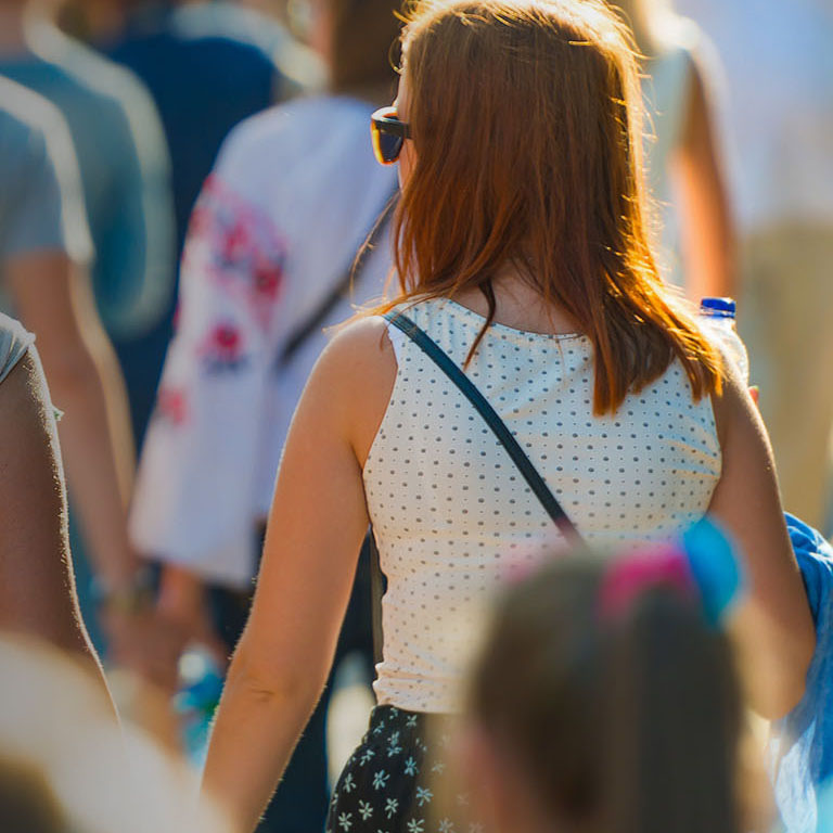 Crowd of people walking on the sunny and busy city street. Soft focus