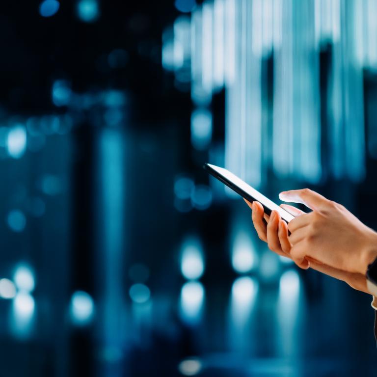 Person using smartphone in city setting with lights