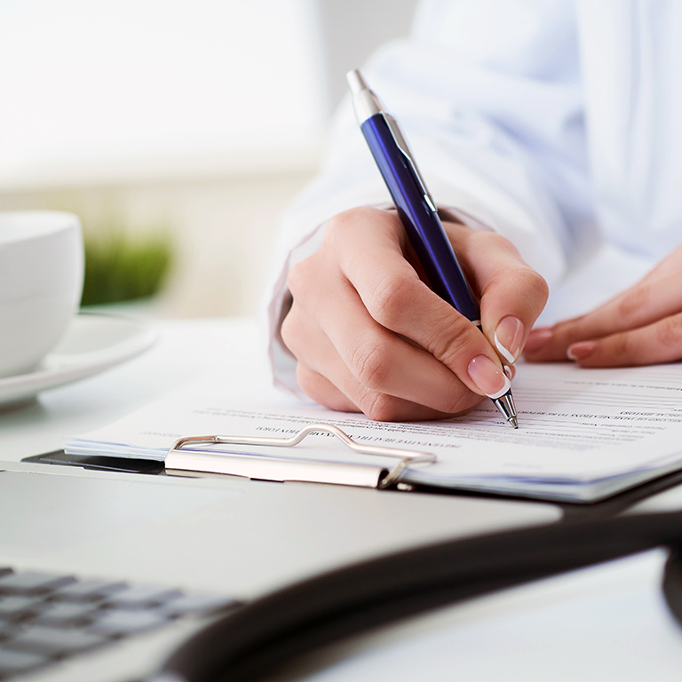 Mid section of female doctor writing prescription to patient at worktable.