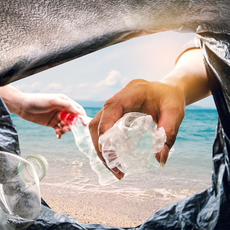 picking up a bottle plastic in to a bin bag and the sea background 768x768