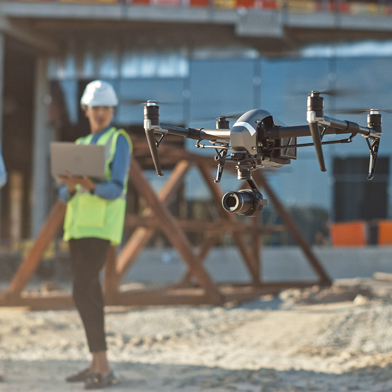 Diverse Team of Specialists Pilot Drone on Construction Site. Architectural Engineer and Safety Engineering Inspector Fly Drone on Commercial Building Construction Site Controlling Design and Quality