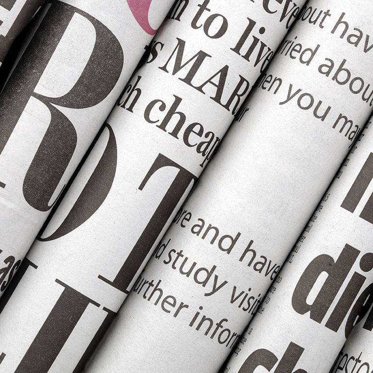 Newspaper headlines shown side on in a stack of daily newspapers