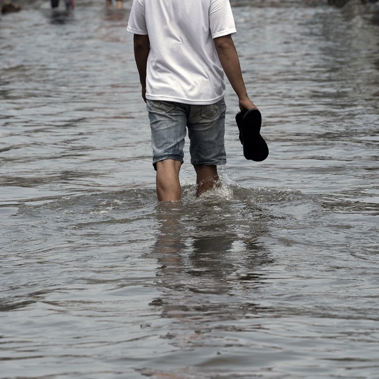 Rear view of a man walking on flood of the street