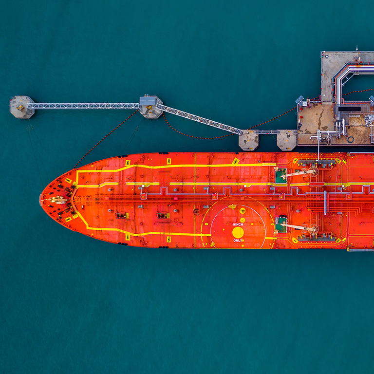 Aerial view red cargo tanker ship vessel at port with marine loading arms, Global business oversea commercial trade logistic import export oil and gas petrochemical from refinery industry transport worldwide.