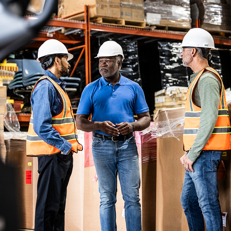 Warehouse workers with safety gear having a quick meeting.