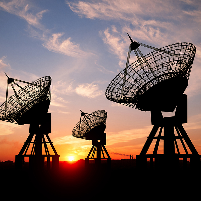 Three satellite dishes at sunset