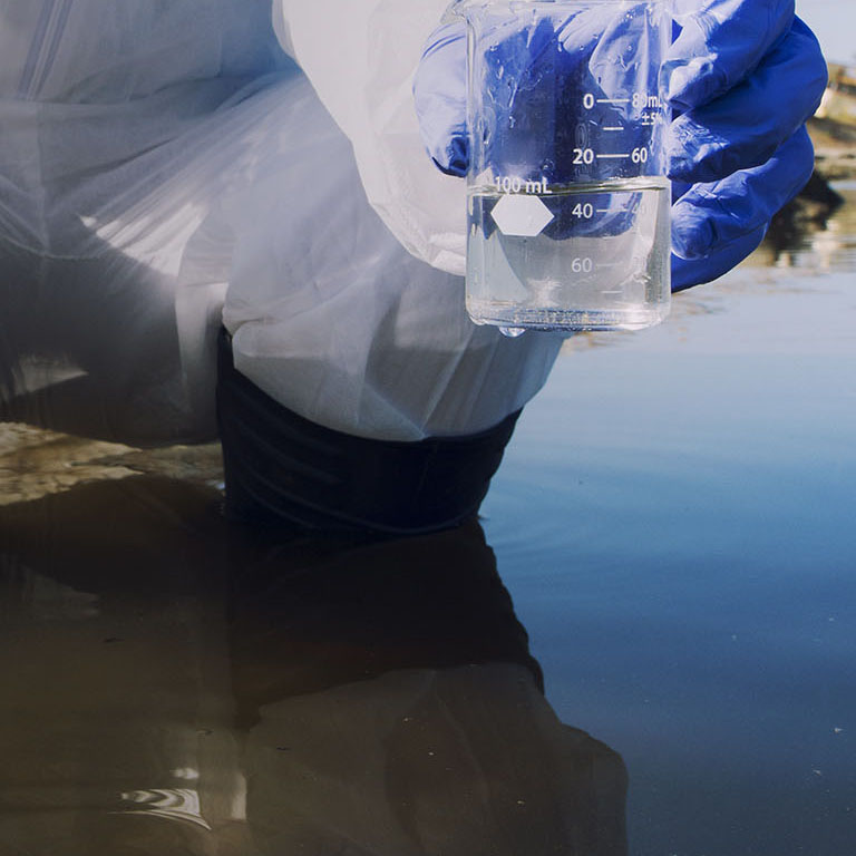 Conserve water and environment. Shot of an unrecognizable ecologist taking samples of water with test tube from city river to determine level of contamination and pollution.