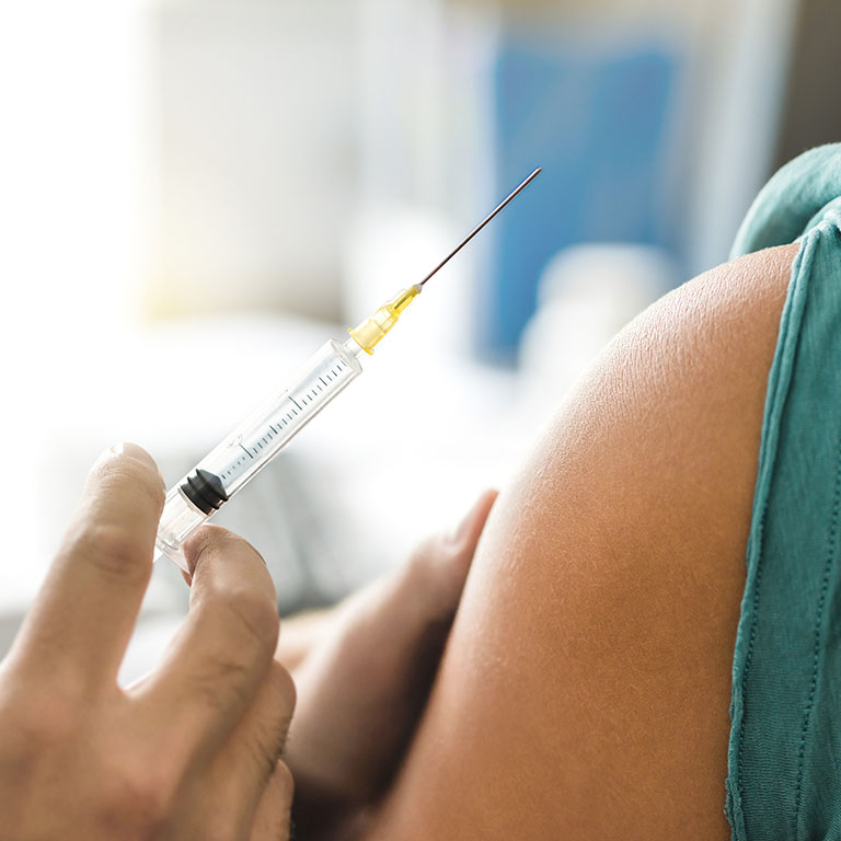 Vaccine or flu shot in injection needle. Doctor working with patient's arm. Physician or nurse giving vaccination and immunity to virus, influenza or HPV with syringe. Appointment with medical expert.