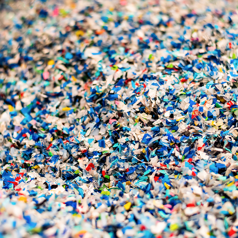 Close view of the multicoloured shredded plastic garbage at waste recycling factory