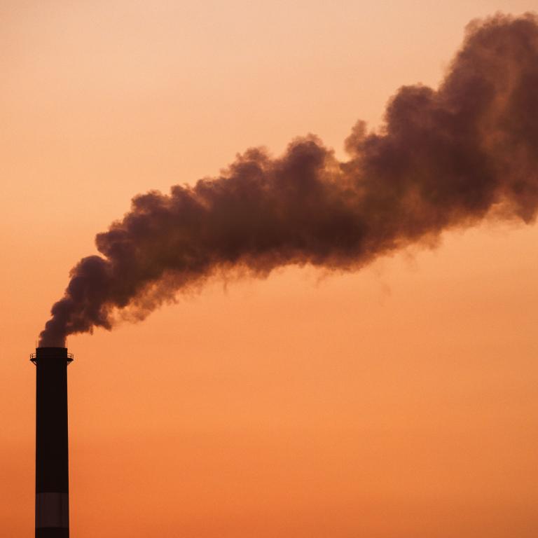 Smoke rises from chimney in industrial area