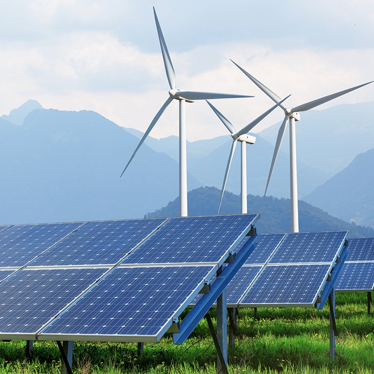 solar panels and wind turbines on summer landscape with mountains on background