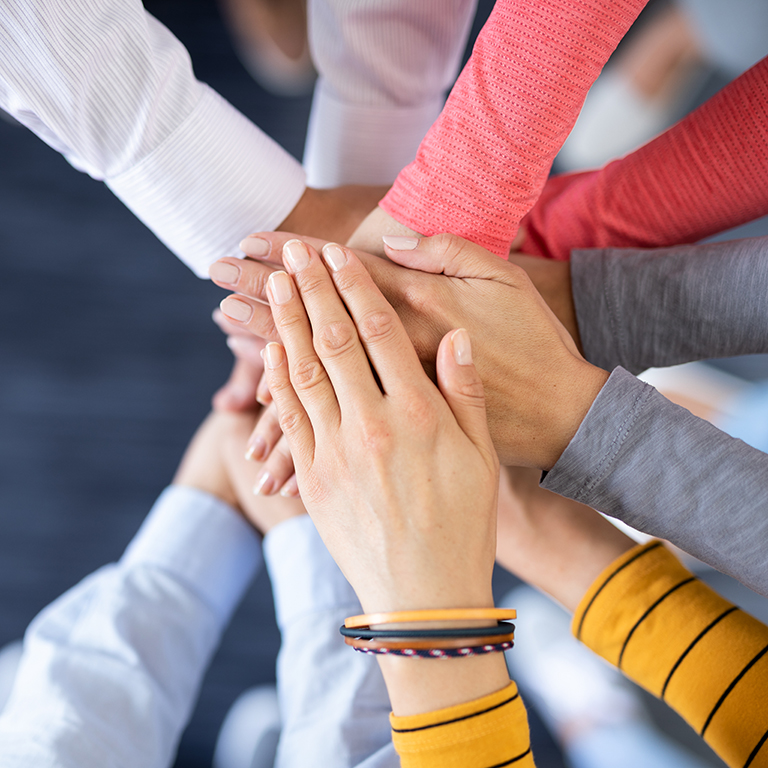 Close up top view of young business people putting their hands together. Stack of hands. Unity and teamwork concept.